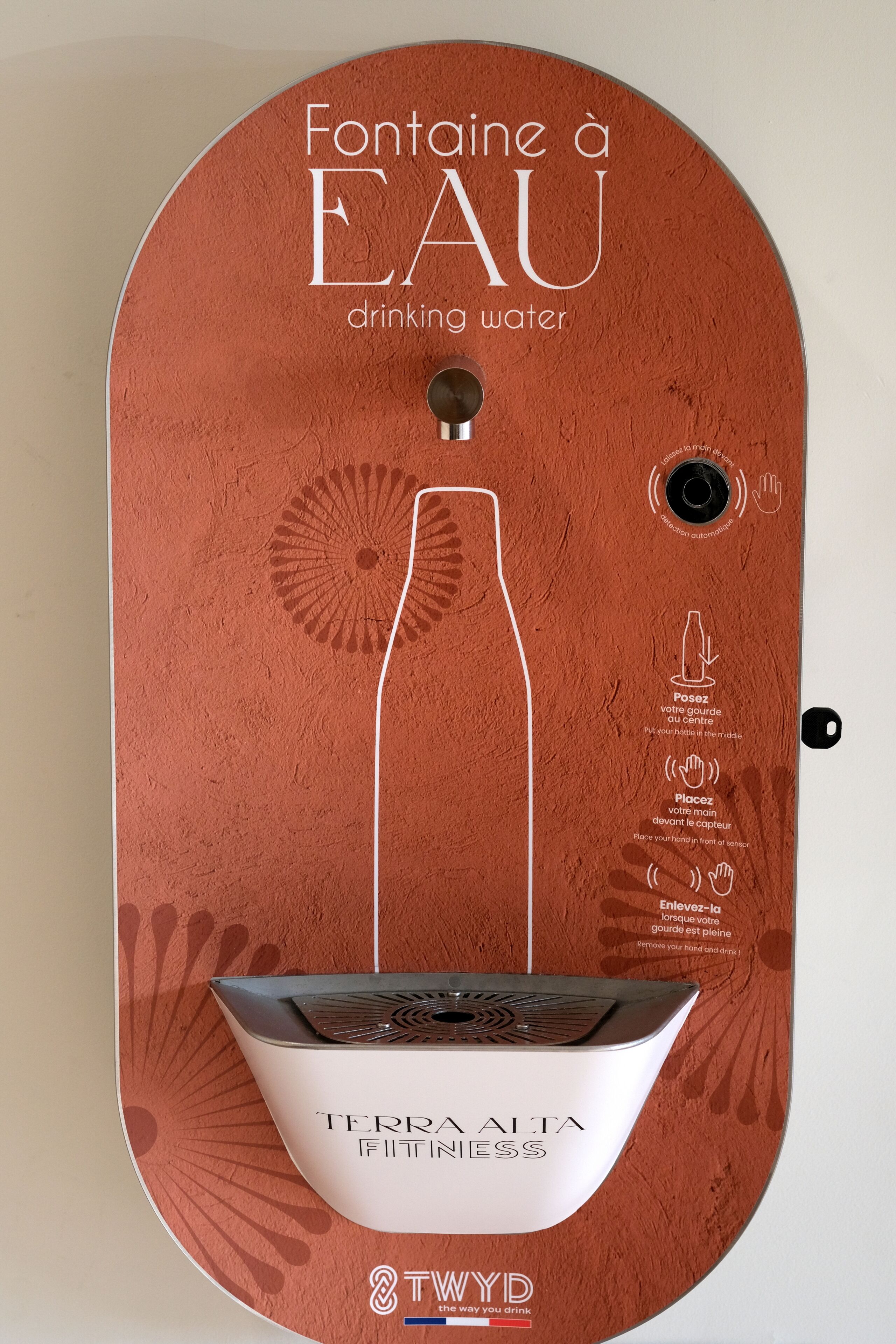 Un dispensador de agua instalado en la pared, con indicaciones de uso.