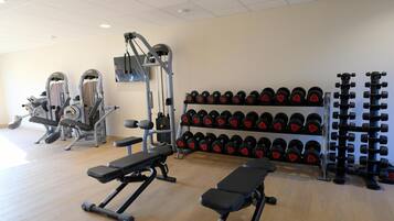 A gym with benches, weight machines, and racks of dumbbells.