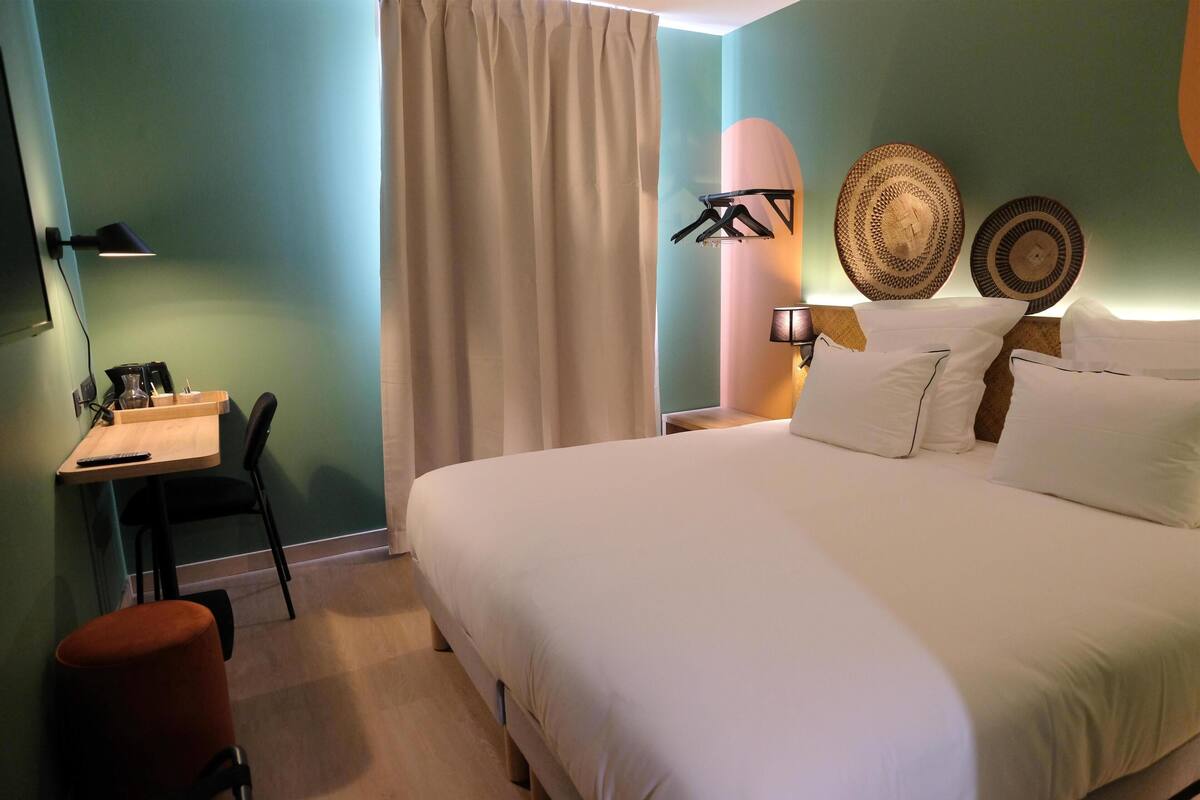 Une chambre à coucher comprenant un lit, un bureau, une chaise, une lampe et des assiettes décoratives.