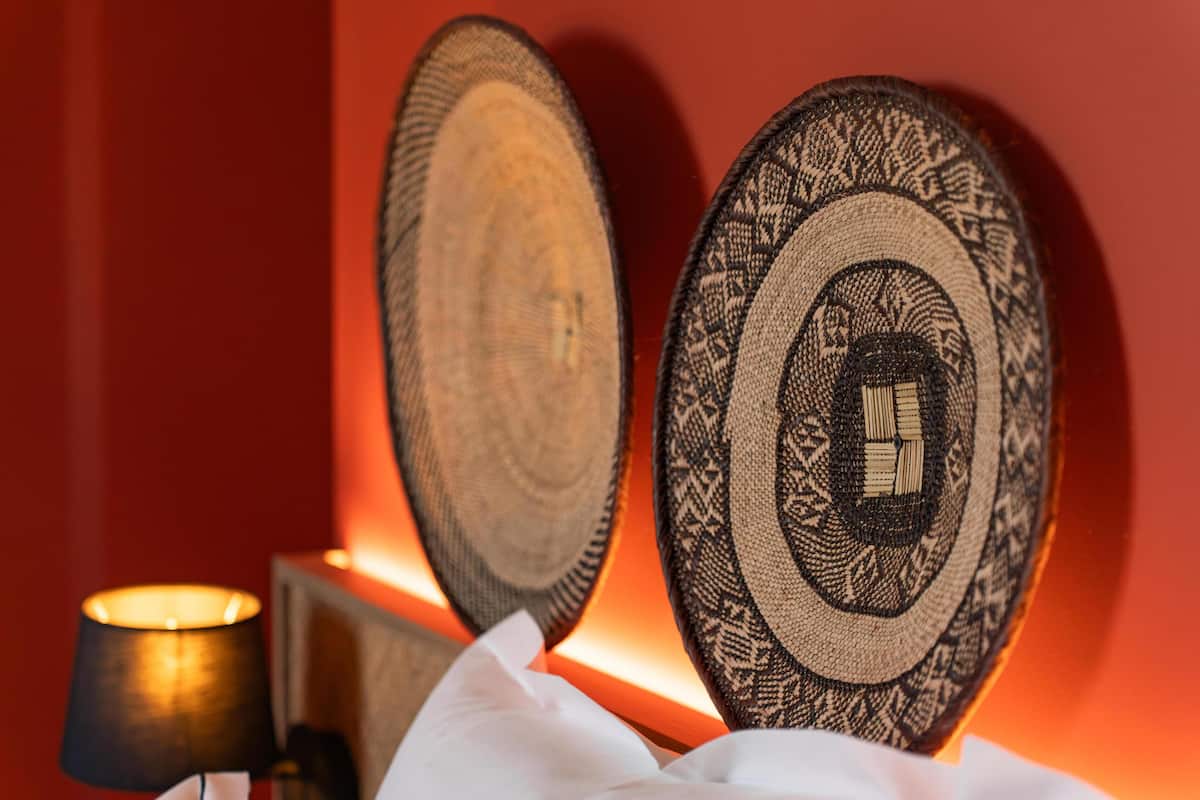 Deux assiettes décoratives fixées au mur, ornées de motifs complexes, une lampe et un tissu blanc posés sur une table.