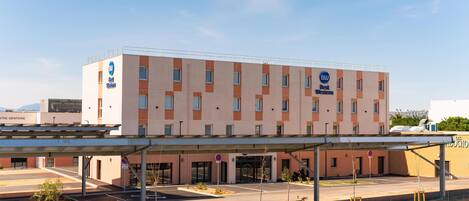 A hotel with a modern design, a covered entrance, and a parking area.