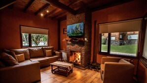 A cozy living room with a stone fireplace, a television mounted above it, and comfortable seating.