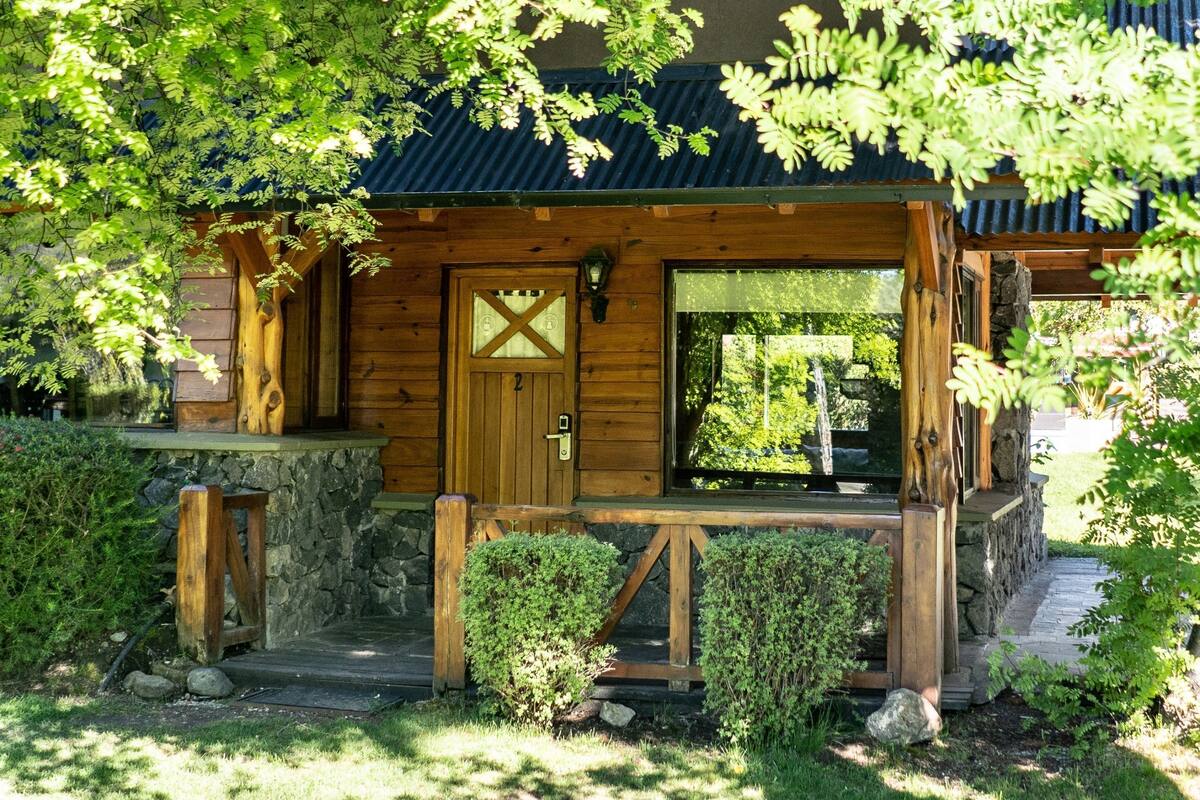 Une cabane en bois avec des fondations en pierre, une véranda en bois et une grande fenêtre.