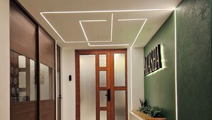 Un hall d’hôtel moderne avec une porte en bois, un comptoir d’accueil et un mur végétal agrémenté d’une enseigne.