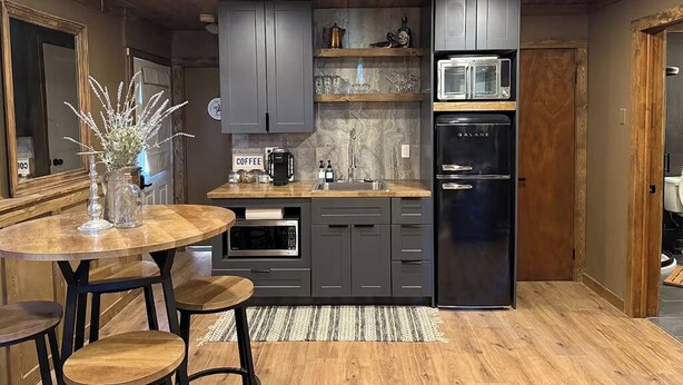 A modern kitchen with grey cabinets, a black refrigerator, a microwave, and a coffee station. - NEW Pickles Point - Western Mountain Getaway (Grand Lake)