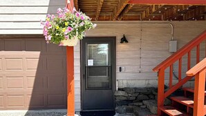 A house with a garage, a front door, a stone wall, and a wooden staircase. - NEW Pickles Point - Western Mountain Getaway (Grand Lake)