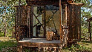 Eine rustikale Holzhütte mit einem Reetdach, großen Glasfenstern und einer Holzterrasse.