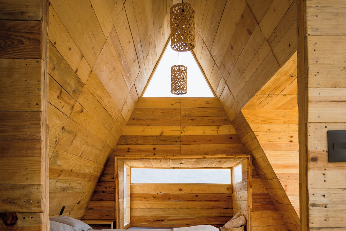 A cozy attic bedroom with a sloped ceiling, a bed, and a small window.