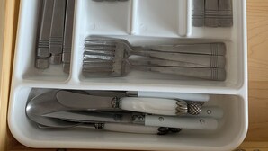 A white tray with cutlery including knives, spoons, and forks.