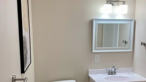 A bathroom with a toilet, sink, and mirror.