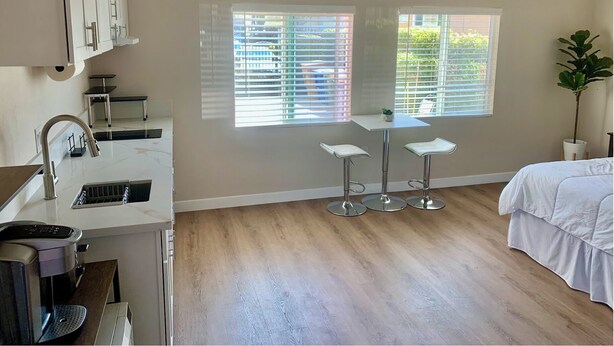 A modern kitchen with a built-in sink, a coffee machine, and a small dining area with stools.