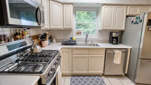 Una cocina con armarios blancos, estufa de acero inoxidable, microondas y refrigerador.