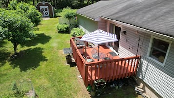 Ein Haus mit einem umzäunten Garten, einer Terrasse mit Gartenmöbeln und einer Garage.