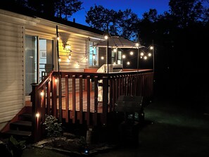 A wooden deck with string lights, a covered area, and a staircase leading to a door. - Catskills Getaway: 3BR Retreat w/ Media Room, Near Casino, Bethel Woods & More! (Glen Wild)