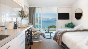 A modern hotel room with a balcony, a dining area, and a large bed. - Couples Retreat - Million Dollar Wakatipu Views! (Queenstown)