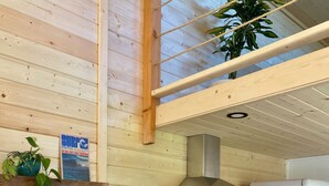A modern kitchen with wooden walls, a stainless steel stove, and a white refrigerator. - Fletchers Cabin (Ucluelet)