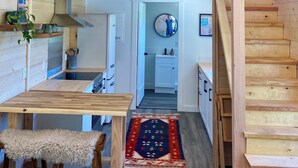 A compact, multi-level wooden cabin with a loft bedroom, a kitchen area, and a dining space. - Fletchers Cabin (Ucluelet)
