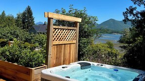 A hot tub on a wooden deck with a view of a lake and mountains. - Fletchers Cabin (Ucluelet)