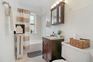 A bathroom with a bathtub, a toilet, a sink, and a mirror. - Peaceful 1BR Escape in Evanston - Hinman (Evanston)