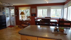 A kitchen with wooden cabinets, a granite countertop, and a dining area with a table and chairs.