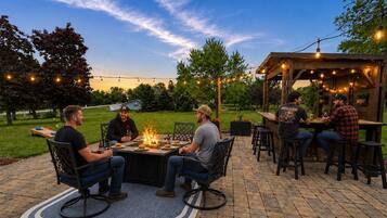 An outdoor patio with a fire pit, seating, and string lights.