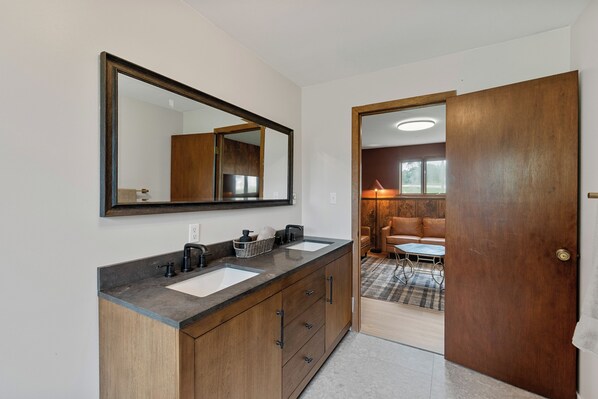 A bathroom with a double sink, wooden cabinets, and a large mirror.