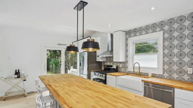 A modern kitchen with a wooden island, stainless steel appliances, and pendant lighting.