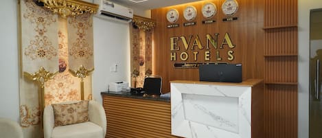 A reception area with a wooden reception desk, a plush armchair, and a wall with clocks and city names.