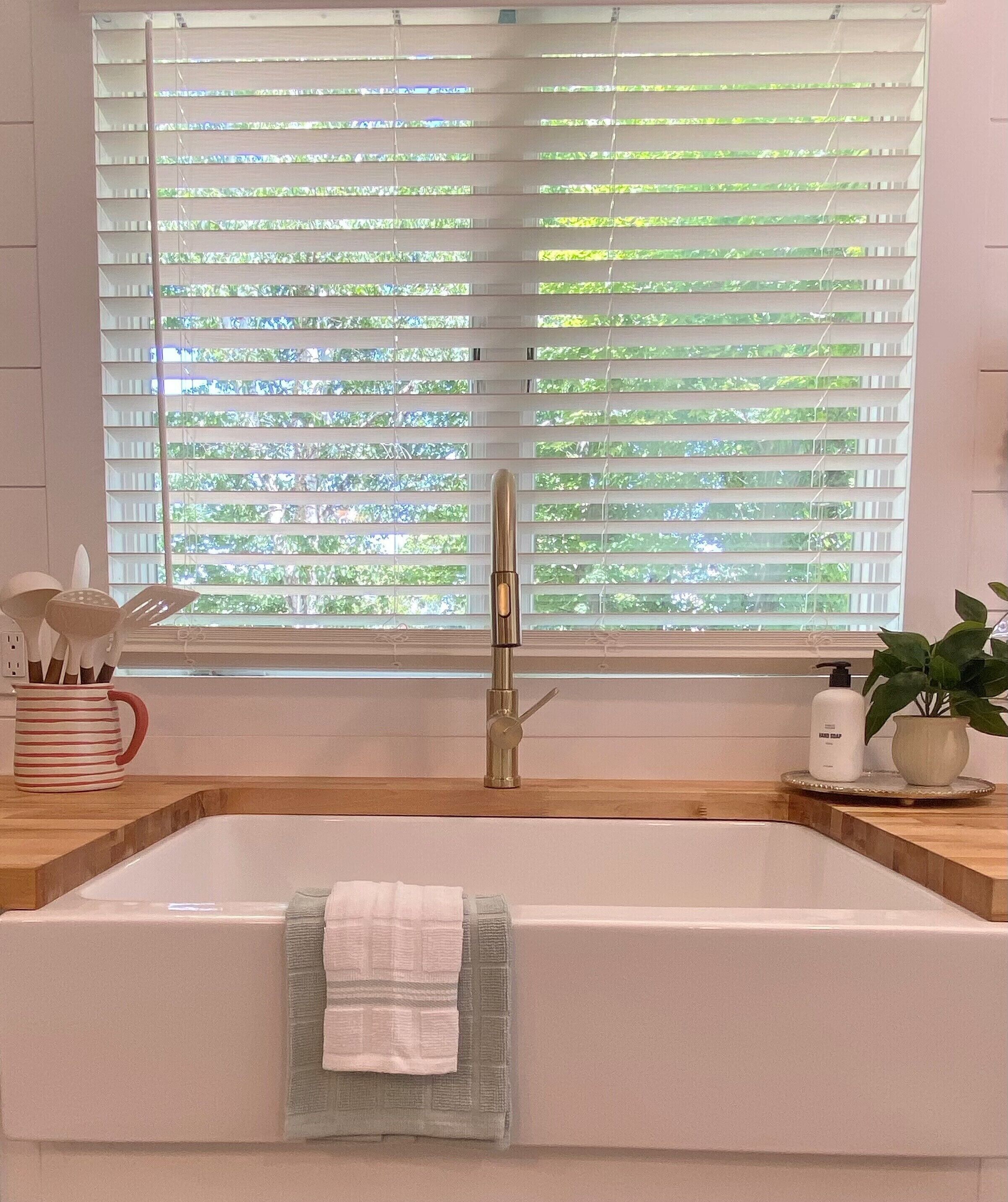 A modern bathroom with a large bathtub, a faucet, and a window with blinds.