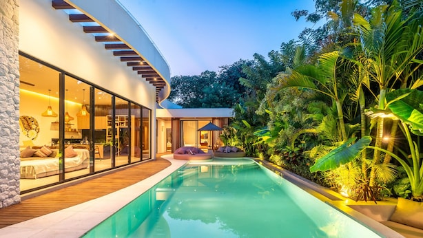 Ein modernes Haus mit Pool, großen Fenstern und einer Holzterrasse.
