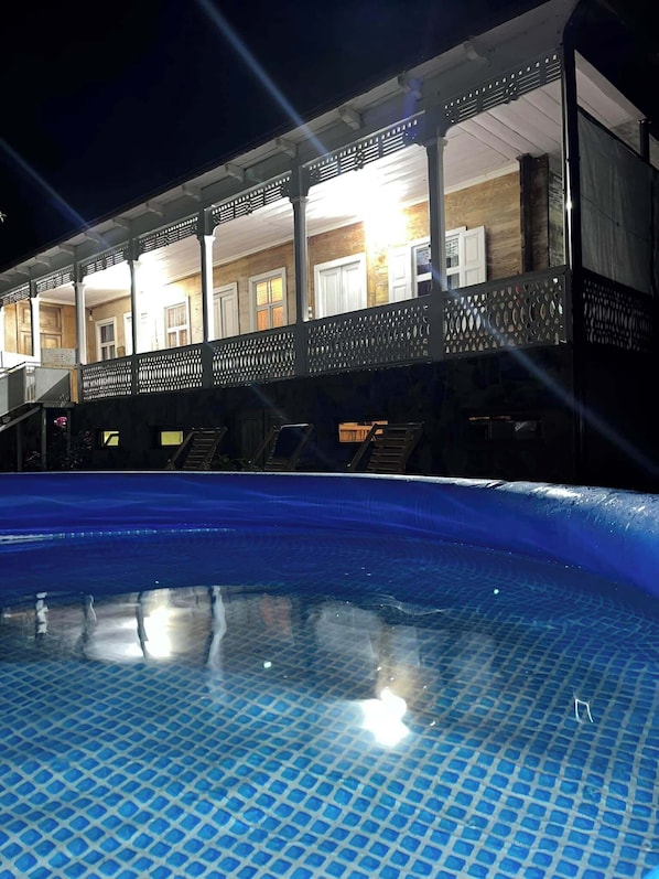 A poolside view of a hotel with a covered outdoor area and a swimming pool.