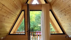 A triangular wooden room with two beds, a skylight, and a view of a deck and trees. -  chalet in amazing village Tsesi with big history and beautiful view (Tsesi)