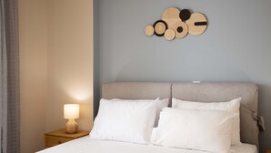 A neatly made bed with white linens, a wooden headboard, and a wall-mounted wooden art piece. - Kalamata City Nest Ypapanti Cozy Bright Getaway (Kalamata)