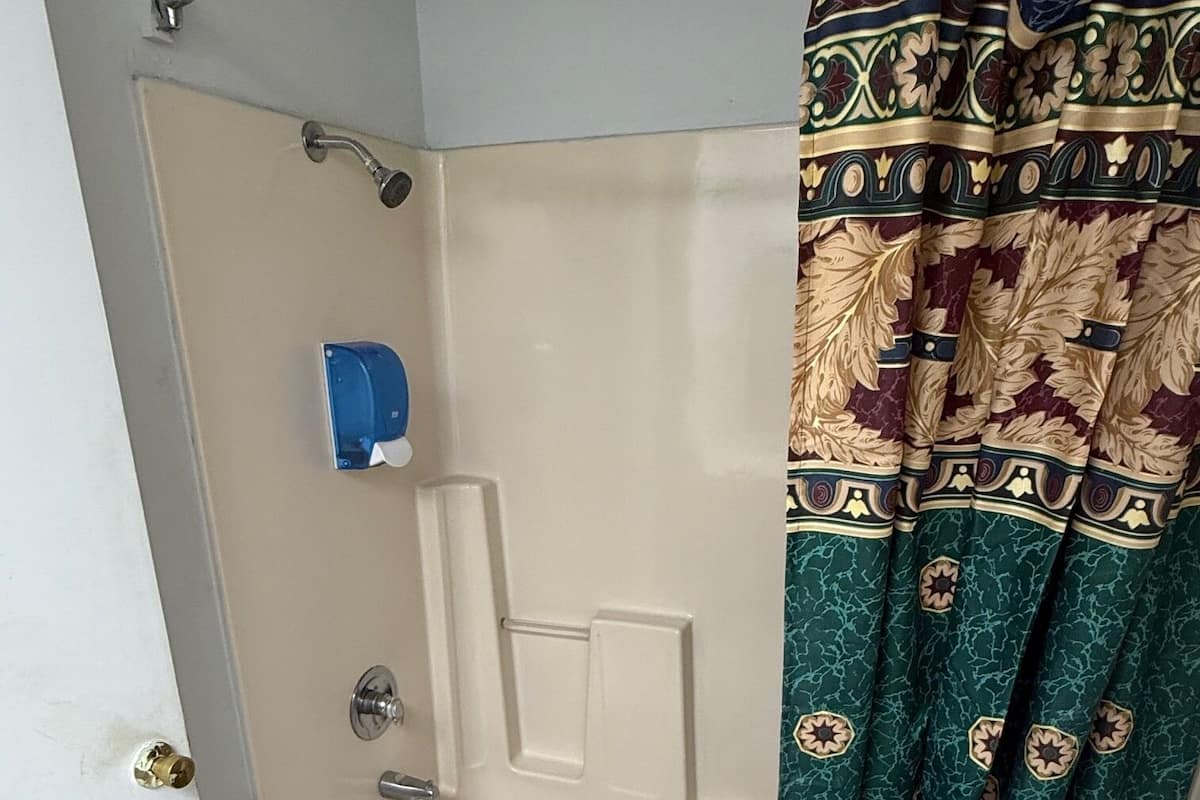 A bathroom with a bathtub, a shower curtain, and a towel rack.