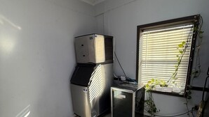 A small, tiled room with a window, a wall-mounted air conditioner, and a small refrigerator. - holiday motel (Springhill)