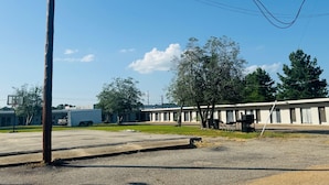 A motel with a row of rooms, a parking lot, and a grassy area. - holiday motel (Springhill)