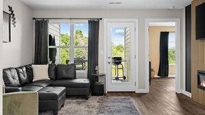 Un salon moderne avec un canapé d’angle, une cheminée et une vue sur l’extérieur.