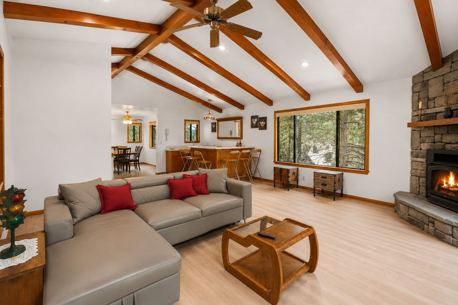 A spacious living room with a fireplace, a dining area, and a kitchen in the background.