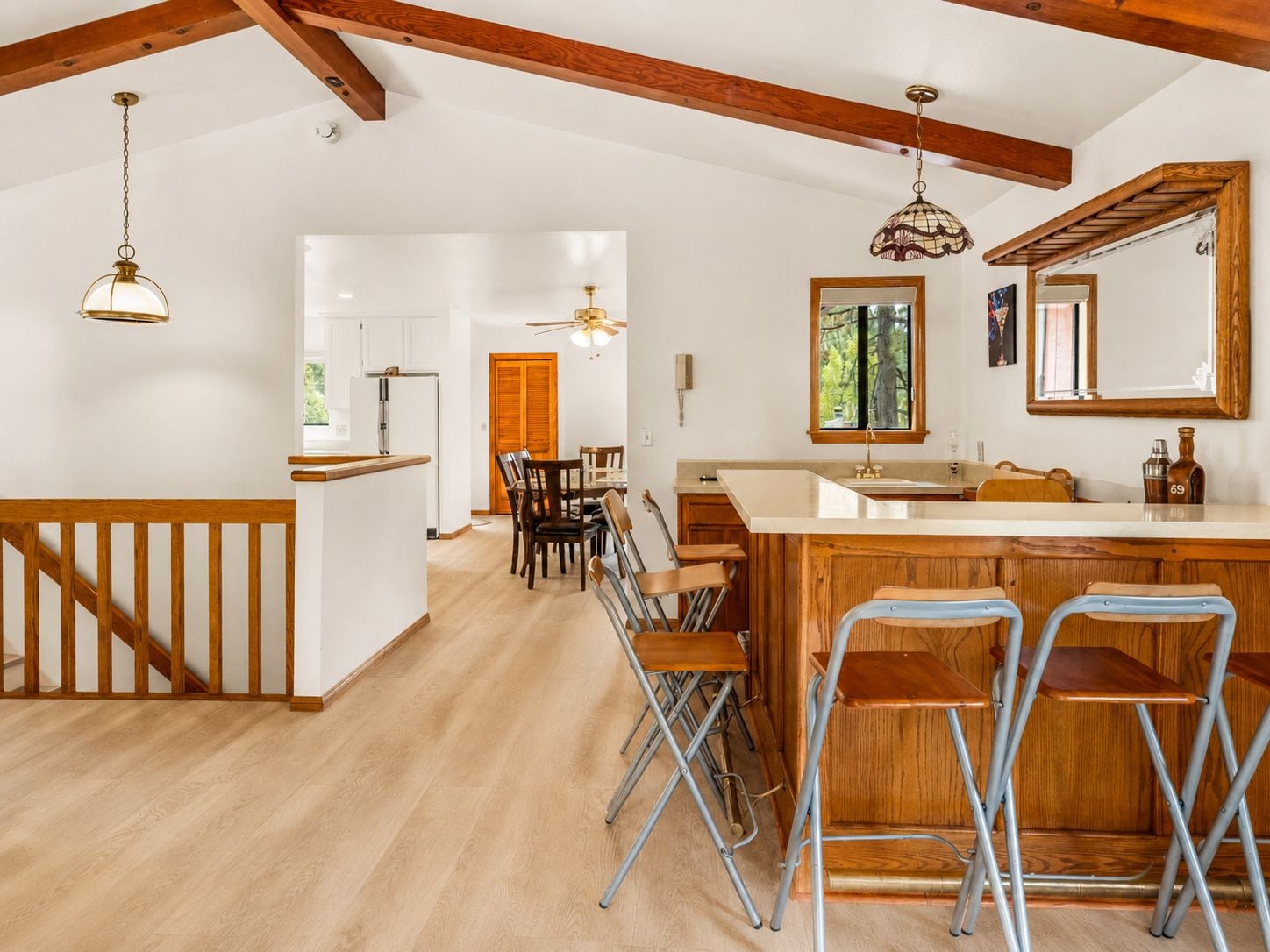 Una cocina amplia con vigas de madera, barra y zona de comedor con sillas.