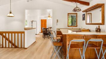 Una cocina amplia con vigas de madera, barra y zona de comedor con sillas.