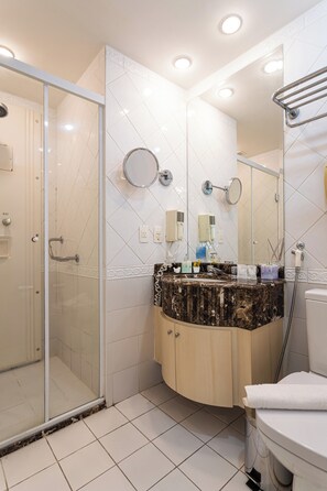 Une salle de bain moderne avec une douche à parois de verre, un lavabo en marbre et des toilettes.