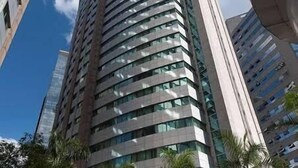 Un hotel moderno e slanciato con facciata curva, ampie finestre e un ingresso centrale con gradini.