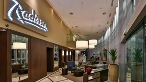 Una hall d'albergo moderna con reception, area salotto e ampie finestre.