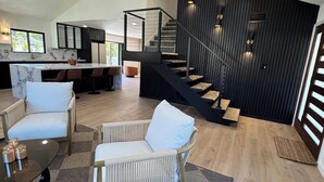 Un vaste espace de vie comprenant une cuisine moderne, un escalier et des coins salon.