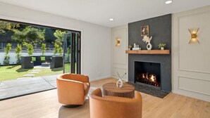 Un salon moderne doté d’une cheminée, d’une grande fenêtre et offrant une vue sur l’extérieur.