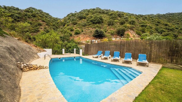 A rectangular swimming pool with a stone border, surrounded by a grassy area and a wooden fence. - El Molinillo de Jimera Jimera de Libar by Ruralidays (Málaga)
