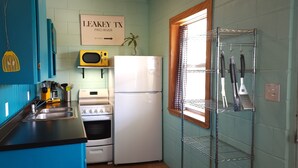 A compact kitchen with a microwave, stove, refrigerator, and a sink. There is a sign on the wall indicating 'Leakey TX Frio River 39 Steps'. - Waterfront on the Frio River, Cozy Cabin, Prime Stargazing (Concan)