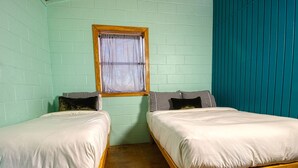 A room with two wooden beds, a window with checkered curtains, teal walls, and a wooden floor. - Waterfront on the Frio River, Cozy Cabin, Prime Stargazing (Concan)