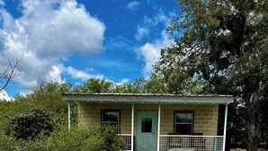 A rustic building with a green door, numbered 5, and a small porch with a bench. - Waterfront on the Frio River, Cozy Cabin, Prime Stargazing (Concan)