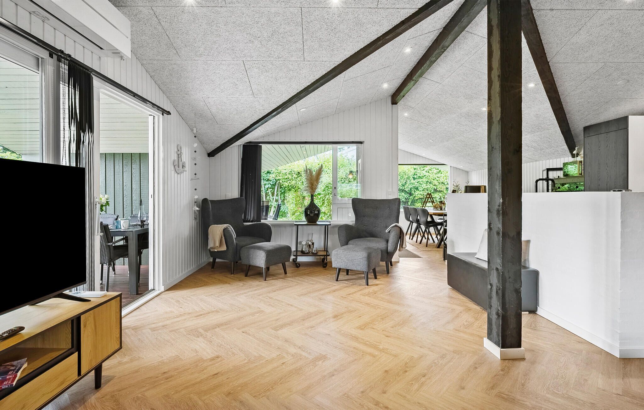 Un vaste espace de vie doté d’un plancher en bois, d’un téléviseur et d’un coin repas avec des chaises et une table.
